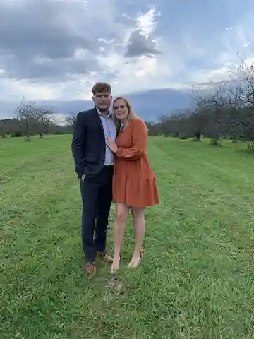 Eli Dean and his wife standing outdoors in an orchard